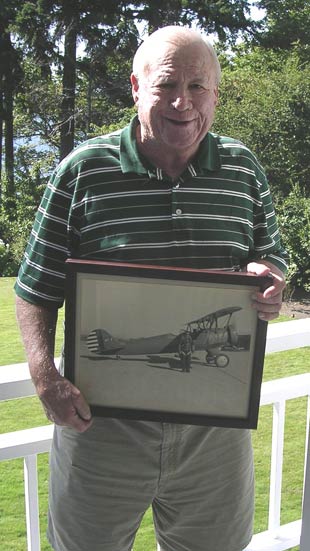 Colonel Hodgson’s Son, Jack N. Hodgson, Holding A Framed Photo Of His Father With An Airplane That Was Attached To The US Embassy In Rome. Photo Taken At Medina, WA, August 14, 2012 (Source: Woodling)